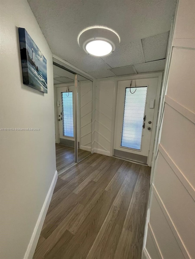 hallway with a paneled ceiling, wood-type flooring, and a healthy amount of sunlight