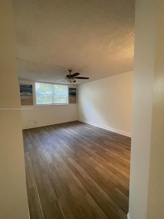 empty room with dark hardwood / wood-style floors, ceiling fan, and a textured ceiling