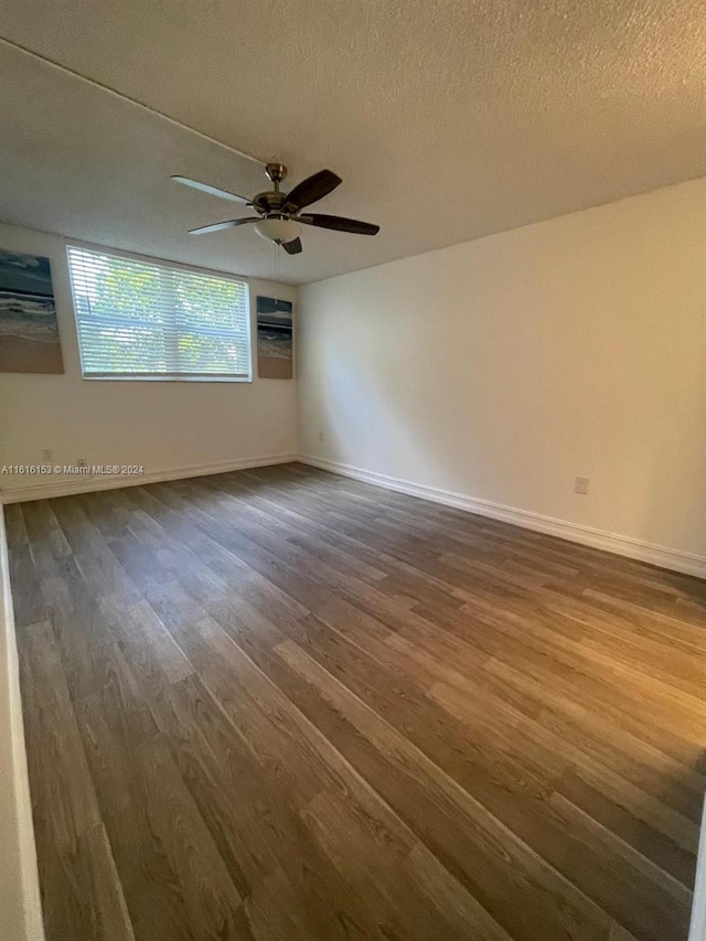 empty room with a textured ceiling, dark hardwood / wood-style flooring, and ceiling fan