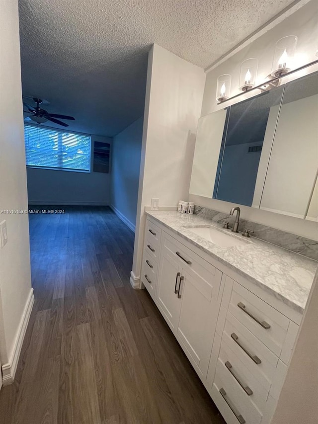 bathroom featuring hardwood / wood-style flooring, a textured ceiling, vanity, and ceiling fan