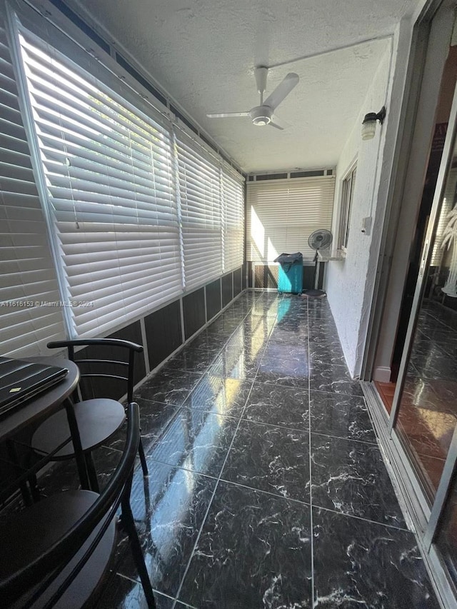 unfurnished sunroom featuring ceiling fan