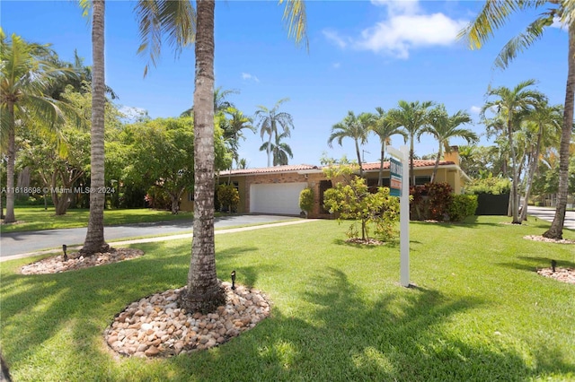 1154 Jefferson St, Hollywood, FL 33019 - view of front facade with an attached garage, driveway, a front yard, and stucco siding