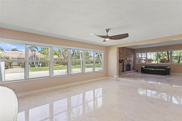 unfurnished living room with a brick fireplace, ceiling fan, and plenty of natural light