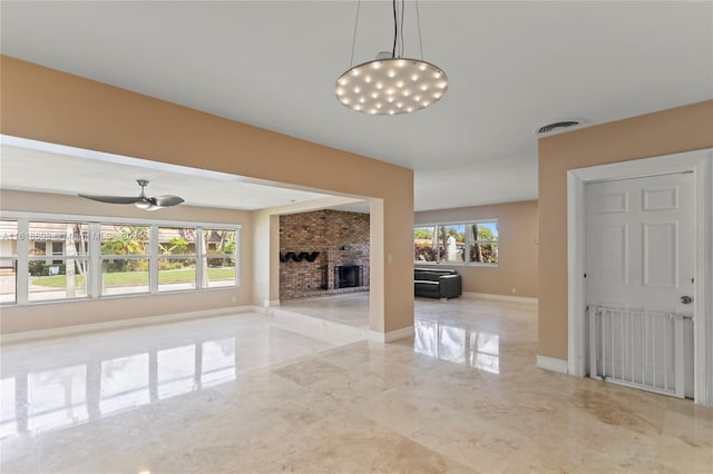 unfurnished living room featuring a fireplace, ceiling fan, and plenty of natural light