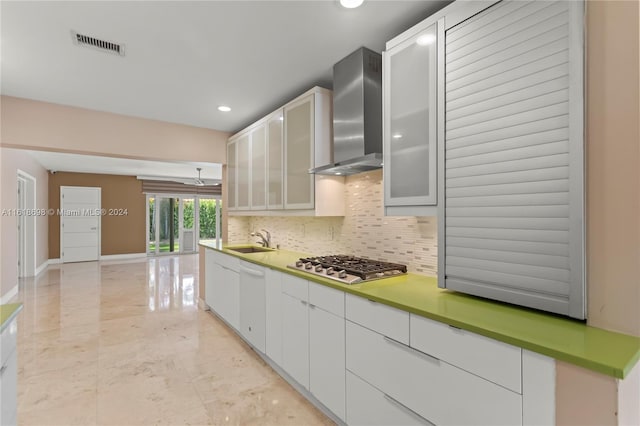 kitchen featuring dishwasher, sink, white cabinetry, stainless steel gas cooktop, and wall chimney exhaust hood