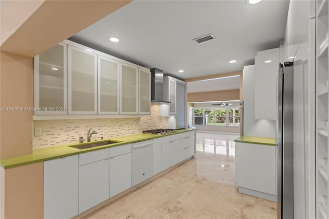 kitchen featuring white cabinets, sink, wall chimney range hood, stainless steel gas stovetop, and dishwasher