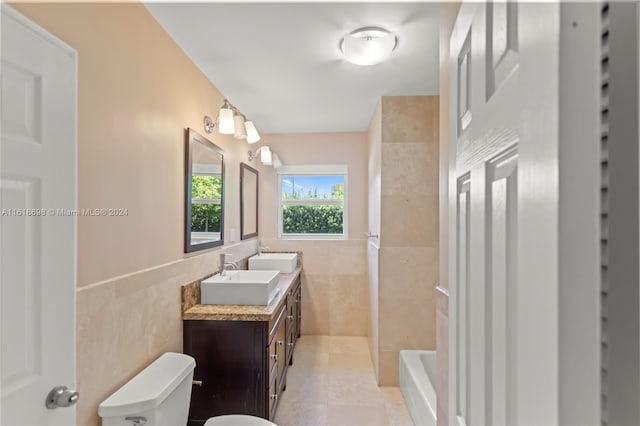 bathroom with a bathtub, tile walls, vanity, tile patterned flooring, and toilet