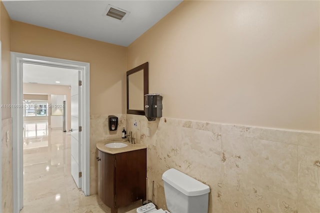 bathroom with tile walls, vanity, and toilet