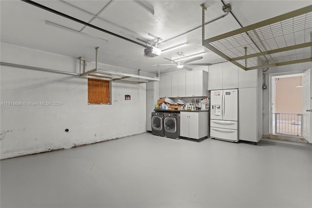 garage featuring white refrigerator with ice dispenser, a garage door opener, and washer and dryer