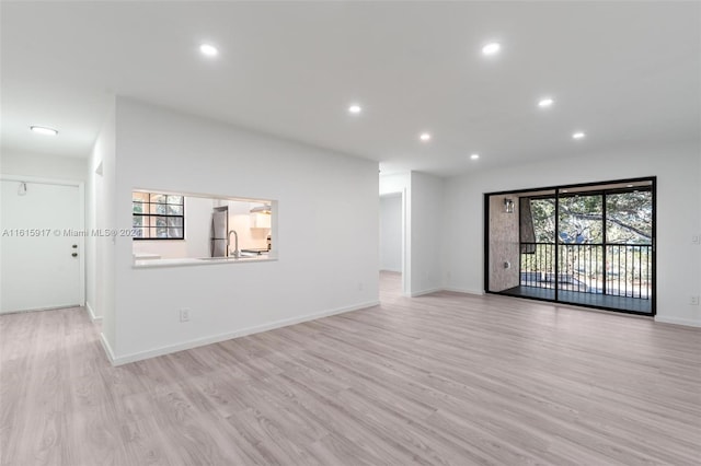 unfurnished living room with light hardwood / wood-style flooring and sink