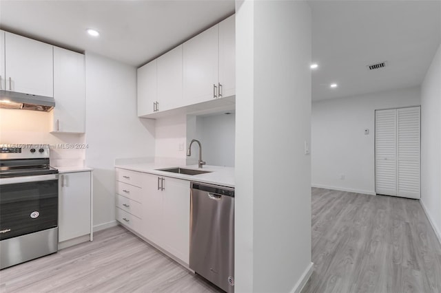 kitchen featuring white cabinets, sink, light hardwood / wood-style flooring, extractor fan, and appliances with stainless steel finishes