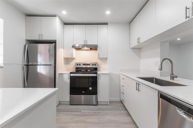 kitchen with light stone counters, sink, white cabinetry, appliances with stainless steel finishes, and light hardwood / wood-style floors