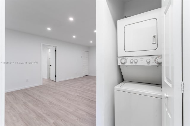 laundry room with stacked washer / dryer and light hardwood / wood-style flooring