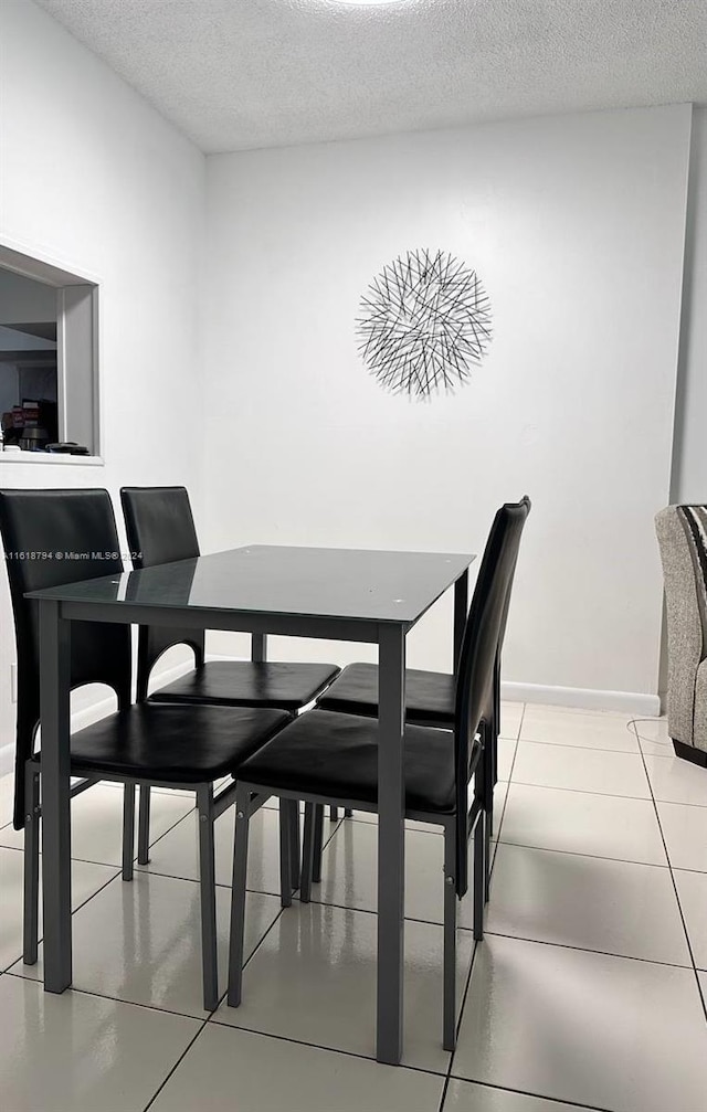 tiled dining space featuring a textured ceiling