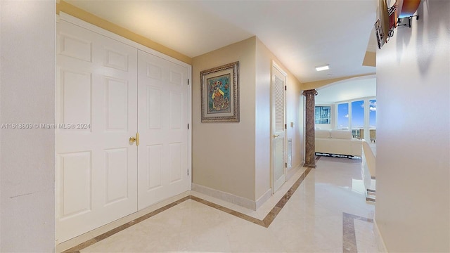 hallway with baseboards, decorative columns, and arched walkways