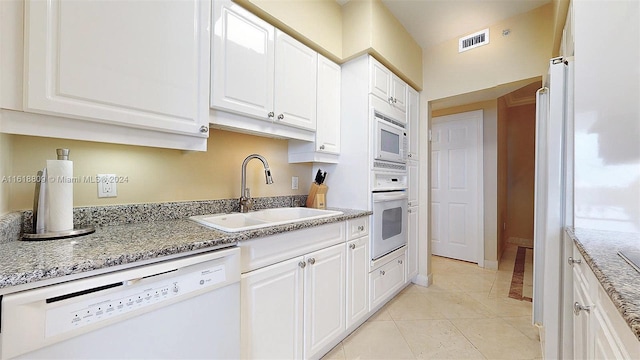kitchen with visible vents, a sink, white cabinets, and white appliances