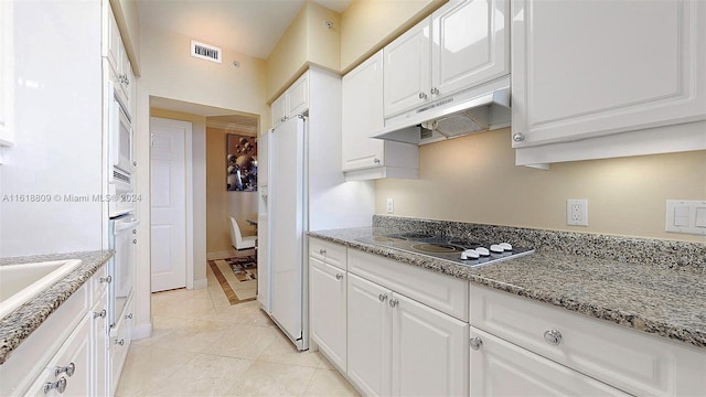 kitchen with under cabinet range hood, white cabinetry, visible vents, and white appliances