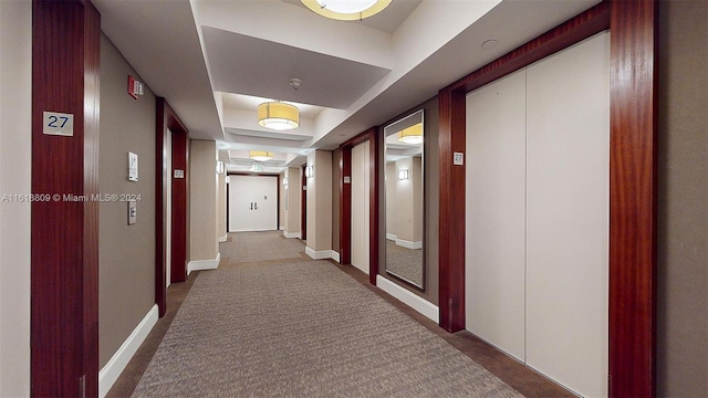 corridor with elevator, carpet floors, and a tray ceiling