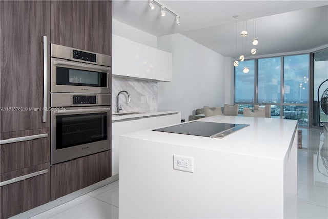 kitchen featuring black electric cooktop, sink, a kitchen island, and white cabinets