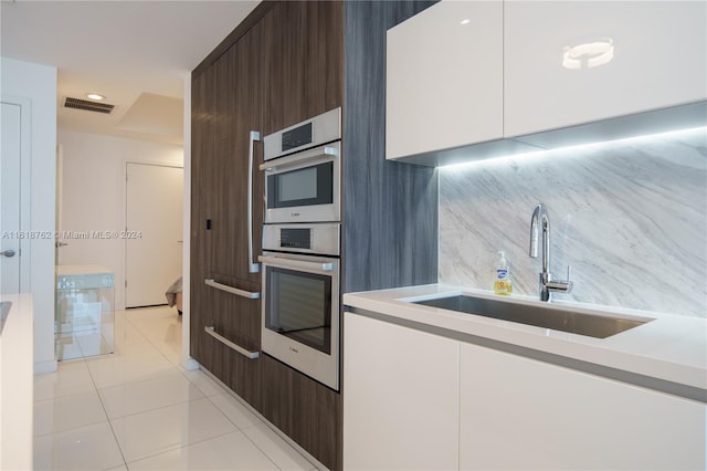 kitchen with light tile patterned flooring, dark brown cabinetry, sink, and white cabinets