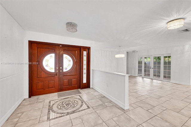 entrance foyer with a healthy amount of sunlight, an inviting chandelier, and french doors