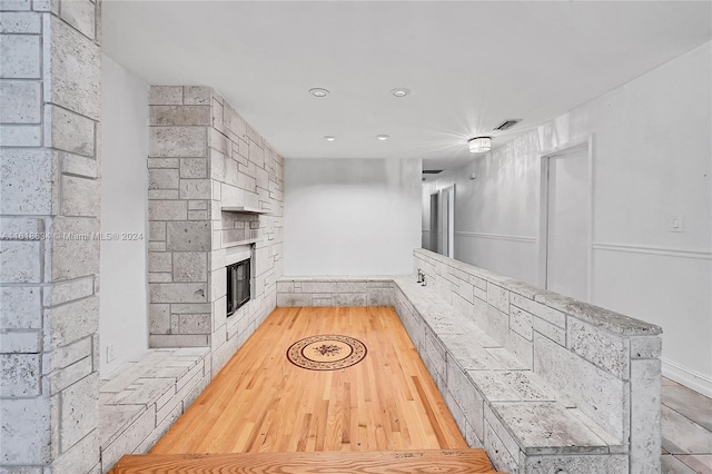 unfurnished living room featuring a stone fireplace and light wood-type flooring