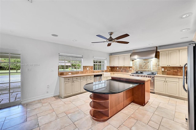 kitchen featuring a center island, backsplash, wall chimney exhaust hood, ceiling fan, and stainless steel appliances