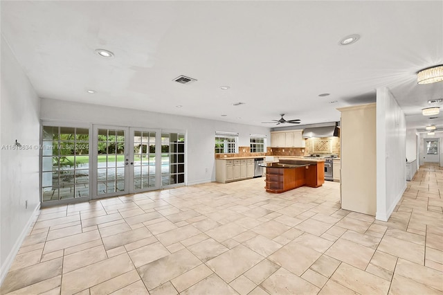 kitchen featuring wall chimney exhaust hood, a healthy amount of sunlight, a kitchen island, and stainless steel appliances