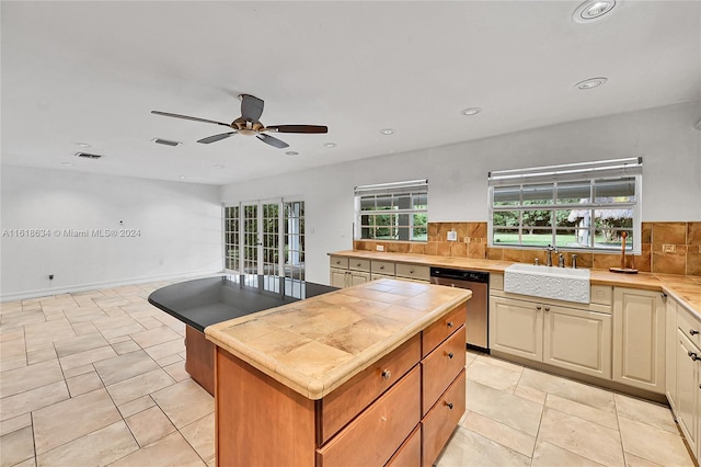 kitchen featuring ceiling fan, tile counters, dishwasher, sink, and backsplash