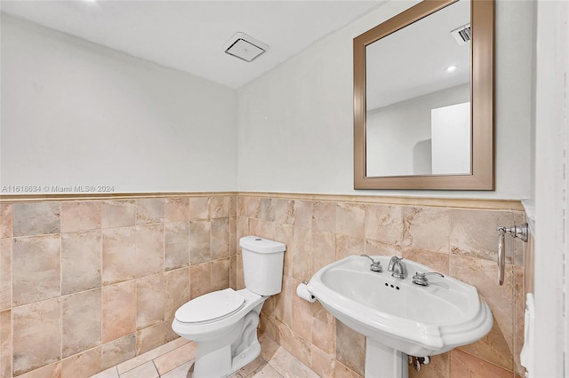 bathroom featuring sink, tile patterned flooring, tile walls, and toilet