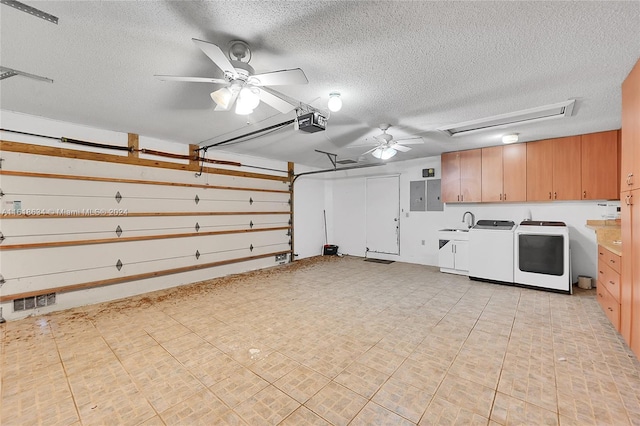 garage featuring electric panel, a garage door opener, sink, ceiling fan, and washing machine and clothes dryer