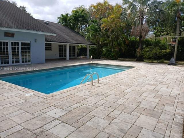 view of swimming pool featuring french doors and a patio