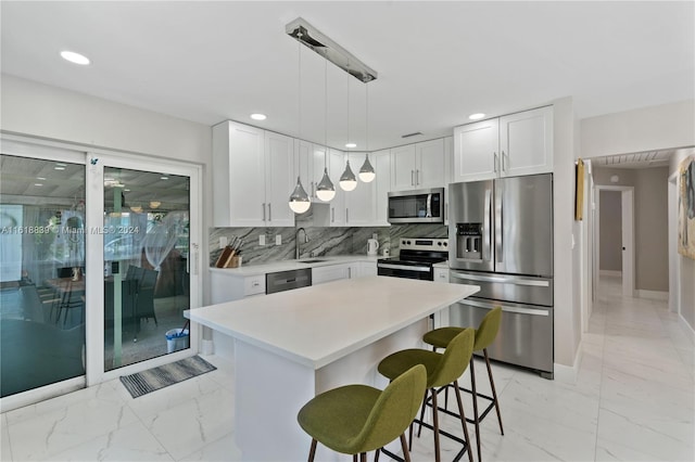 kitchen with white cabinetry, tasteful backsplash, a kitchen island, appliances with stainless steel finishes, and decorative light fixtures