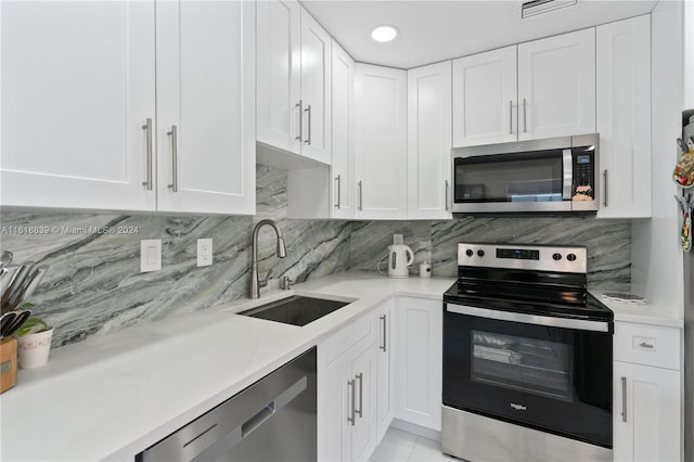 kitchen featuring tasteful backsplash, stainless steel appliances, sink, light tile patterned flooring, and white cabinetry