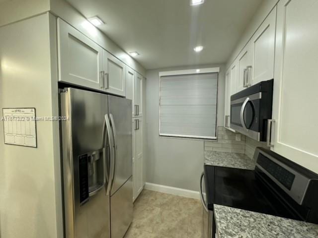 kitchen with backsplash, white cabinetry, light stone countertops, and appliances with stainless steel finishes