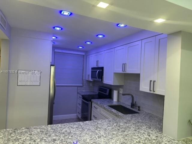 kitchen with sink, decorative backsplash, light stone countertops, white cabinetry, and stainless steel appliances