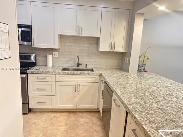 kitchen featuring backsplash, light stone countertops, sink, and appliances with stainless steel finishes