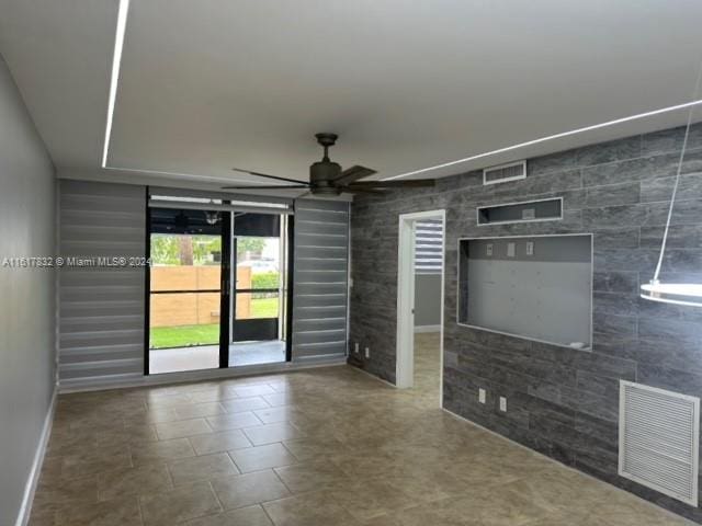 unfurnished room with ceiling fan and tile walls