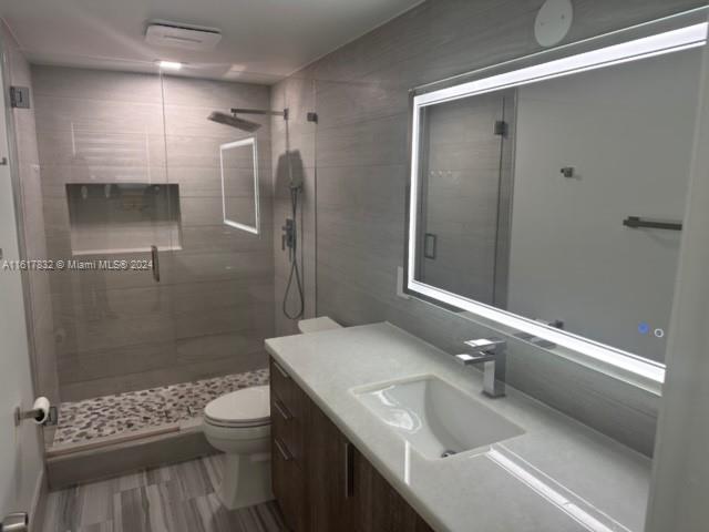 bathroom featuring vanity, toilet, and a shower with shower door