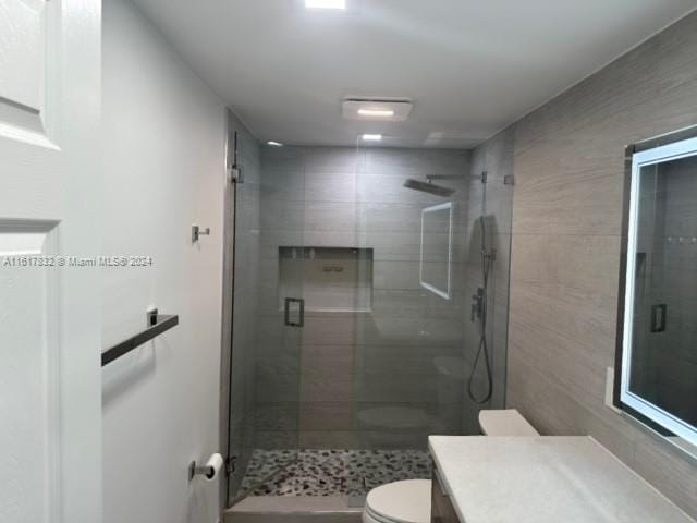 bathroom with vanity, toilet, and a shower with door