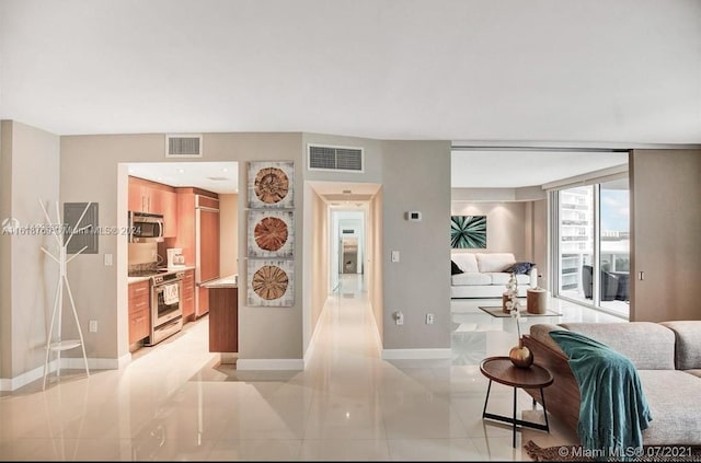 hall with light tile patterned flooring, baseboards, and visible vents