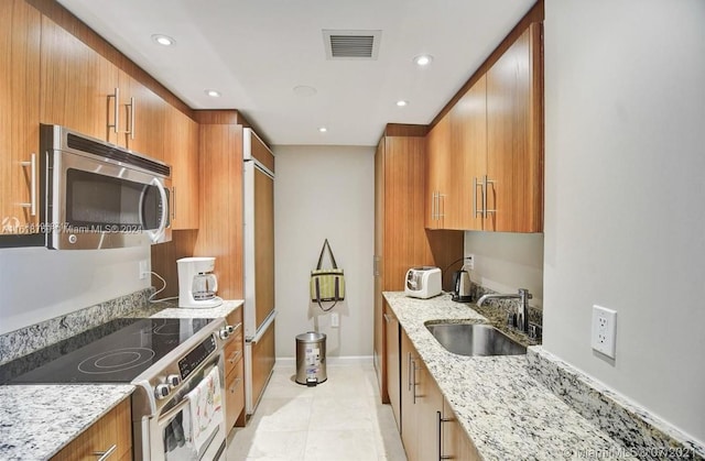 kitchen featuring sink, light stone counters, light tile patterned flooring, and stainless steel appliances