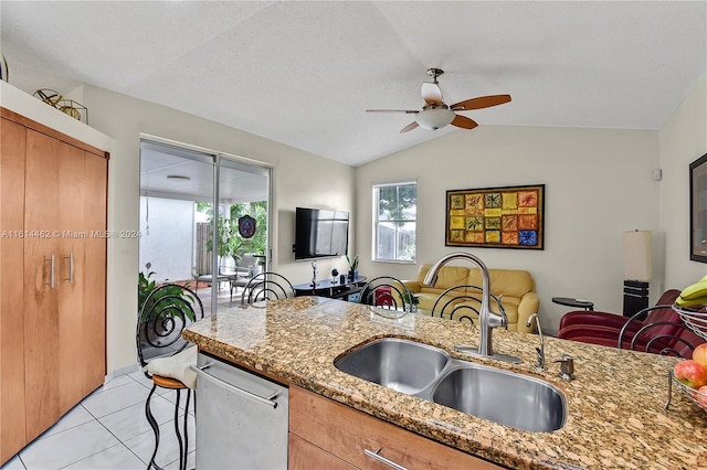 kitchen featuring dishwasher, sink, light stone counters, and lofted ceiling