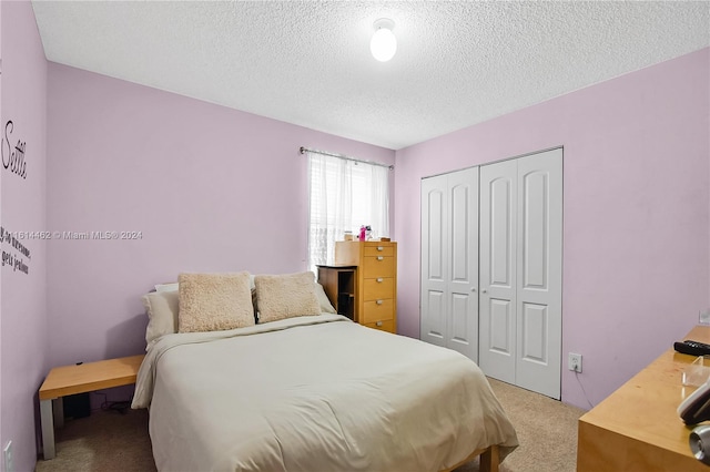 bedroom featuring a textured ceiling, light colored carpet, and a closet