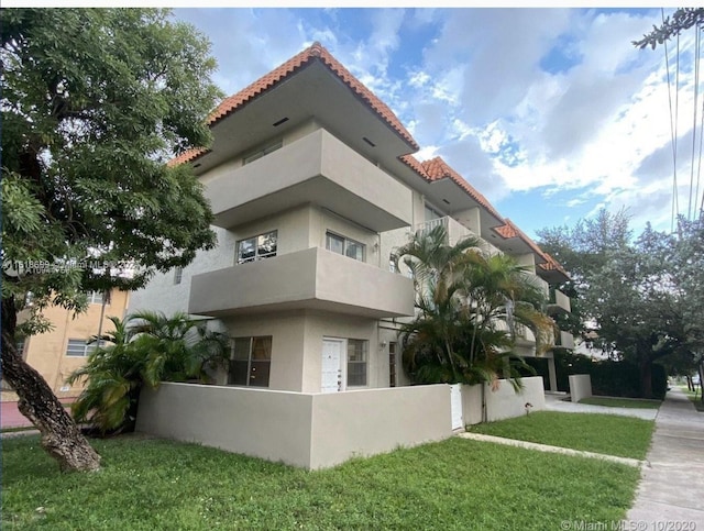 view of property exterior with a yard and a balcony