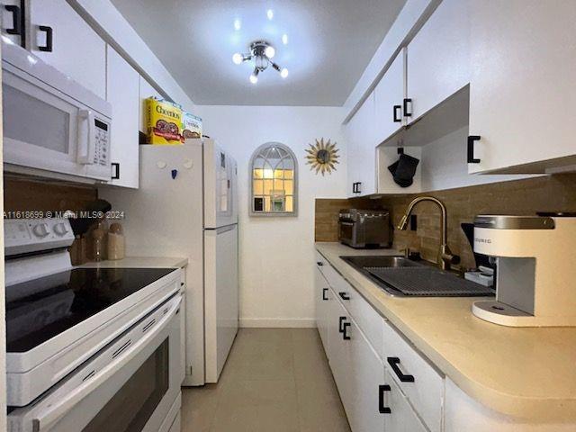 kitchen featuring light tile patterned flooring, white cabinetry, white appliances, decorative backsplash, and sink