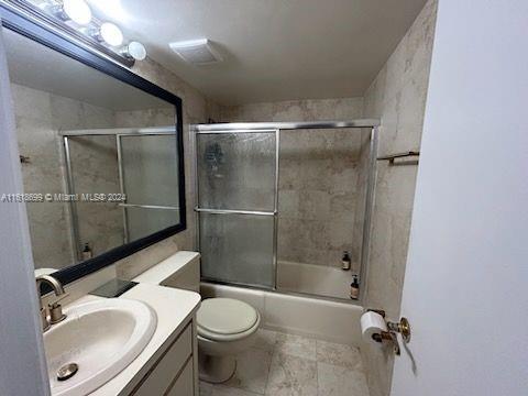 full bathroom with vanity, toilet, tile patterned floors, and enclosed tub / shower combo