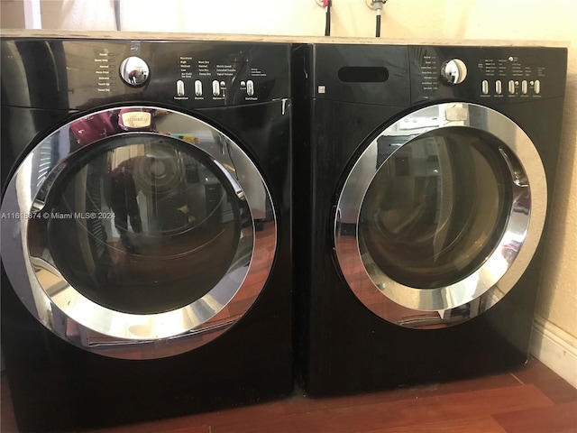 washroom with hardwood / wood-style flooring and washing machine and clothes dryer