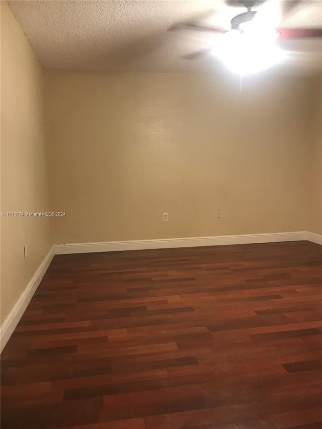 unfurnished room featuring dark hardwood / wood-style floors, ceiling fan, and a textured ceiling