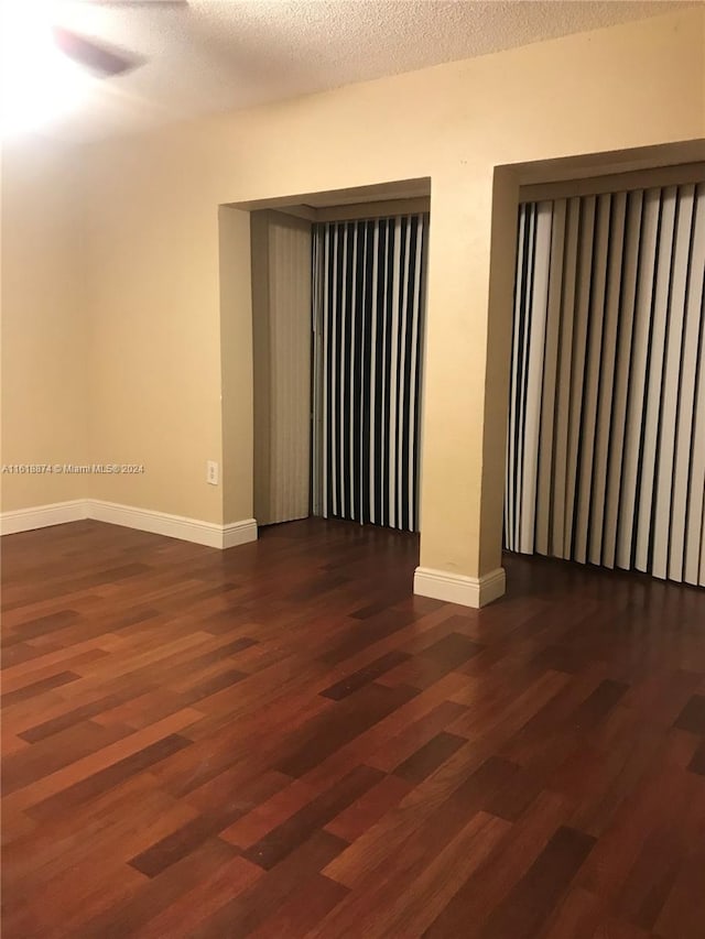 spare room with dark wood-type flooring and a textured ceiling